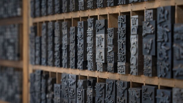 A collection of metal plaques with engraved text, likely used for identification or categorization, displayed on a wooden grid. - Hoshino Resorts KAI Unzen (Unzen)