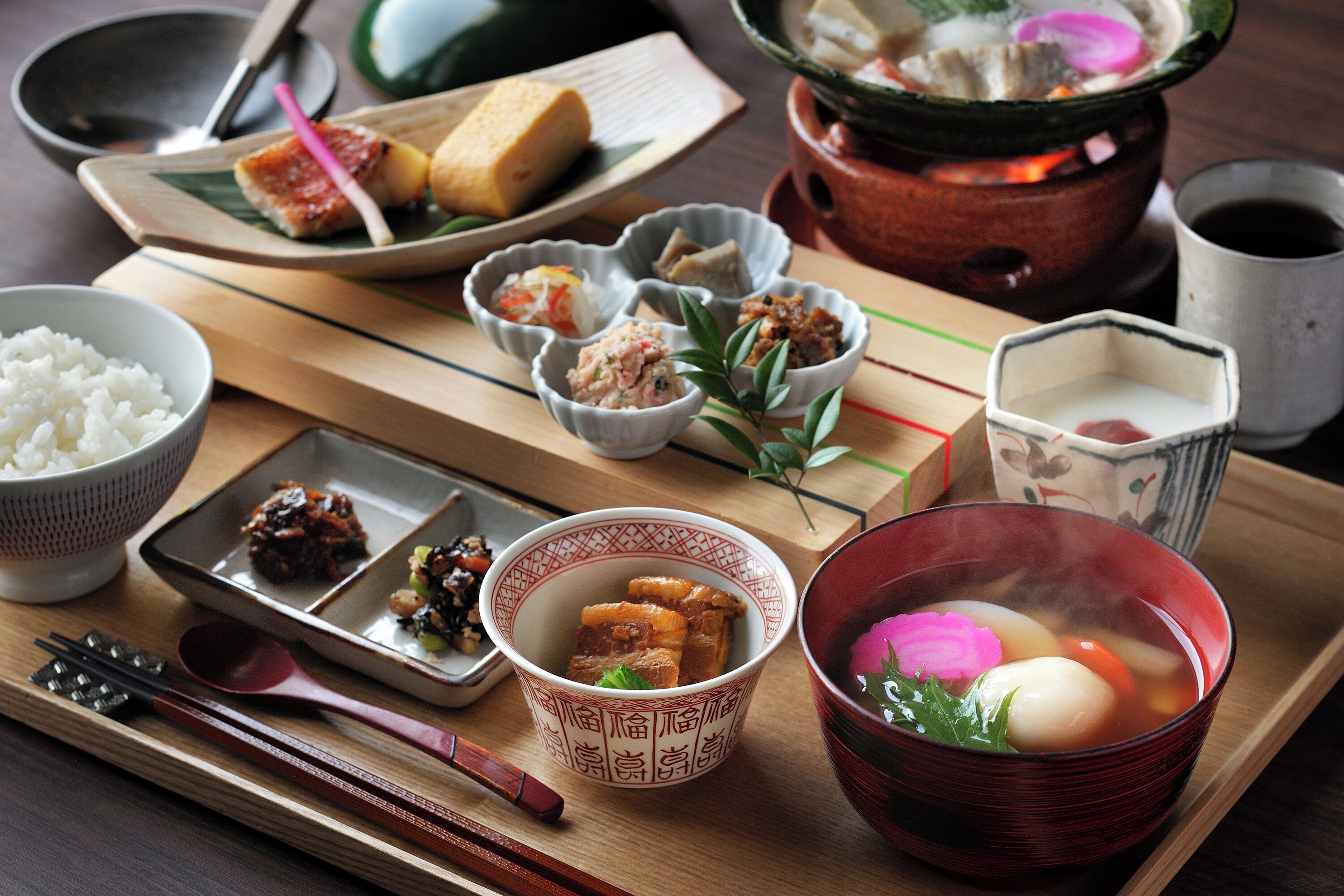 A traditional Japanese meal with various dishes, including rice, soup, and pickled vegetables, served on a wooden tray.