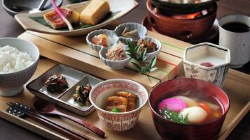 A traditional Japanese meal with various dishes, including rice, soup, and pickled vegetables, served on a wooden tray.
