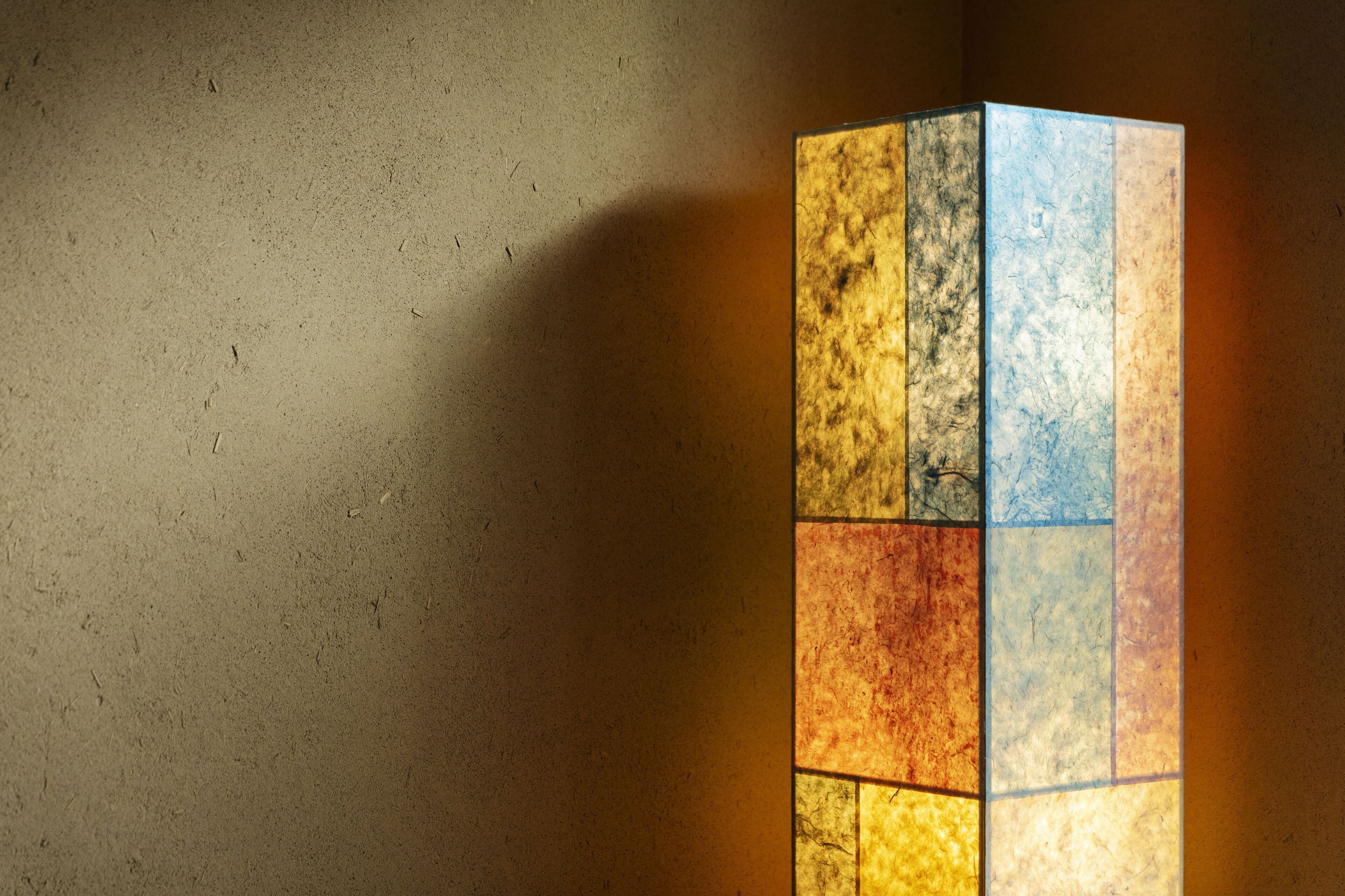 A wall with a textured surface and a vertical, multi-colored panel.