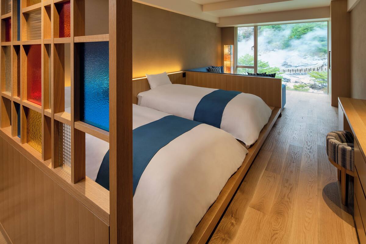 A hotel room with a large bed, a wooden desk, and a view of a waterfall.