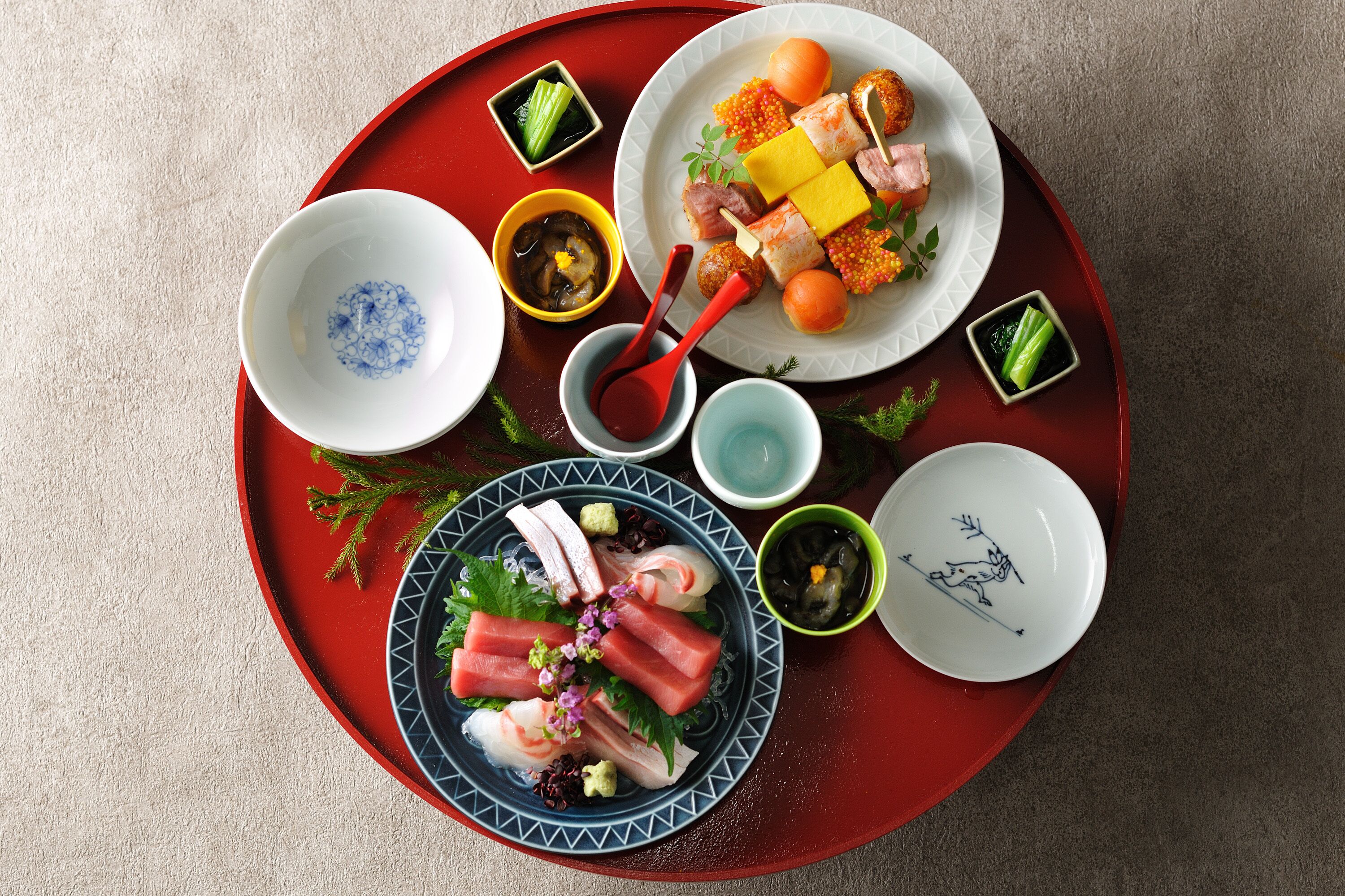 A tray with various dishes including sashimi, sushi, and pickled vegetables.