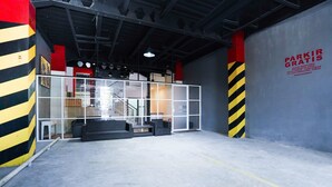 An industrial-style interior with a large grey door labeled "PARKIR GRATIS" and a staircase leading to an upper level. - Flagship 3688 Pot Art (Surabaya)