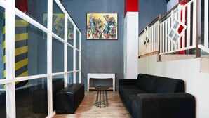 A modern interior with a black sofa, a small round table, and a painting on the wall. - Flagship 3688 Pot Art (Surabaya)