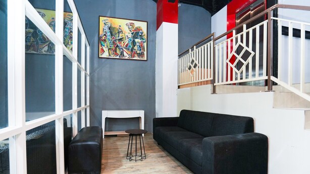 A modern living room with a black sofa, a small round table, and a painting on the wall. - Flagship 3688 Pot Art (Surabaya)