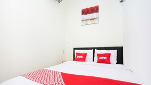 A bed with a white and red bedspread, two red pillows with the word "OYO" on them, and a red and white abstract painting on the wall. - Flagship 3688 Pot Art (Surabaya)