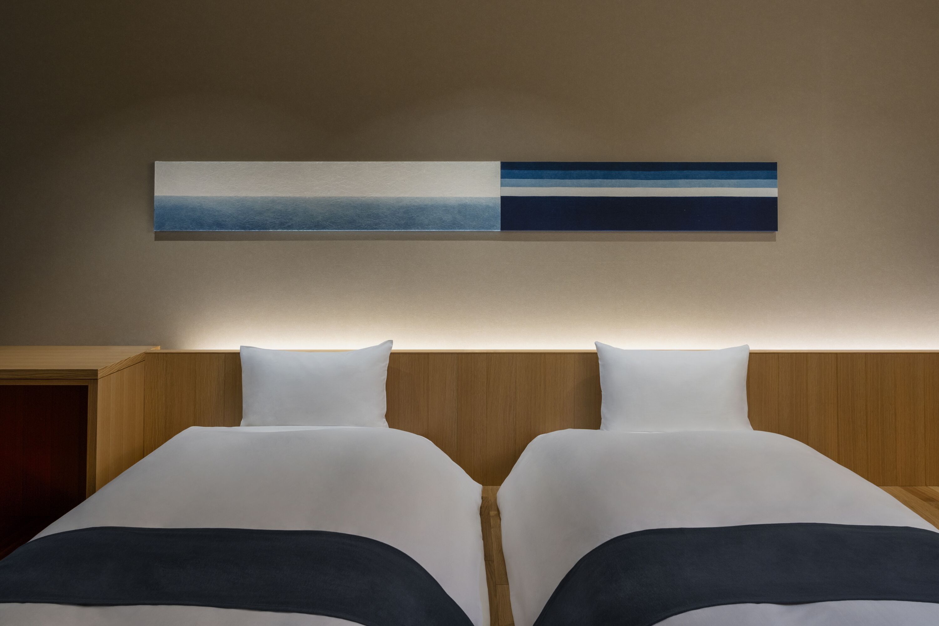 A hotel room with two beds, a wooden headboard, and a wall-mounted artwork.