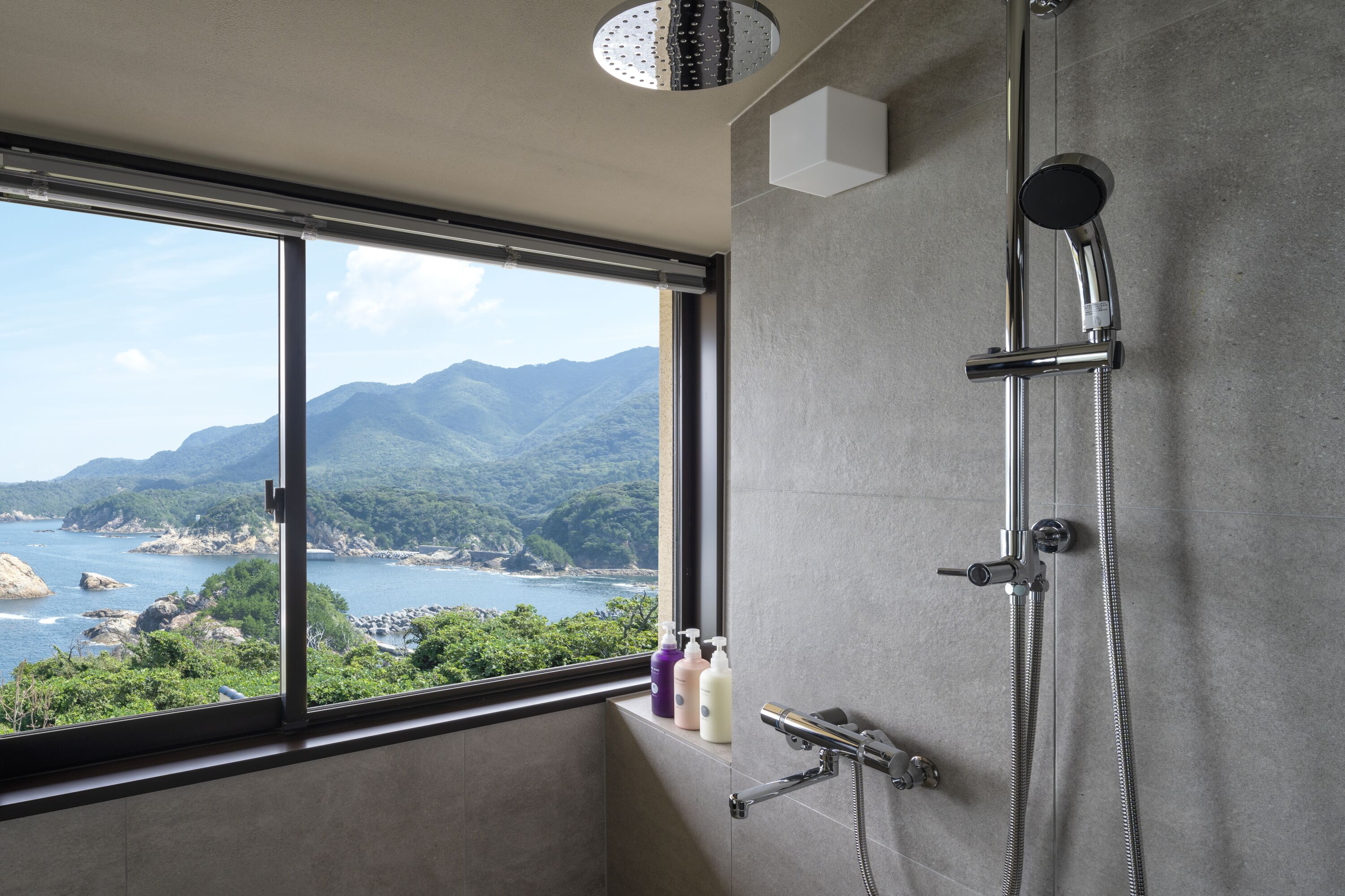 A bathroom with a large window offering a view of mountains and a body of water.