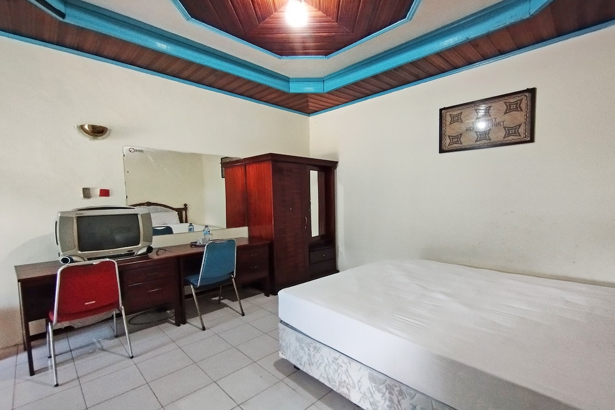 Une chambre à coucher comprenant un lit, un bureau avec une télévision, une chaise, une armoire et un plafond avec des moulures bleues.