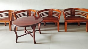 Un coin repas comprenant une table ronde en bois et quatre chaises en bois au dossier incurvé.