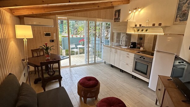 Un intérieur chaleureux en bois, avec un canapé, deux poufs rouges, une table à manger avec des chaises et un coin cuisine comprenant un réfrigérateur, un four et un évier.
