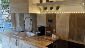 Une cuisine moderne dotée d’un plan de travail en bois, d’appareils électroménagers en acier inoxydable et d’un four encastré.