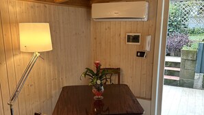 Une pièce aux murs lambrés, comprenant une table à manger, des chaises, une lampe et un appareil de climatisation.