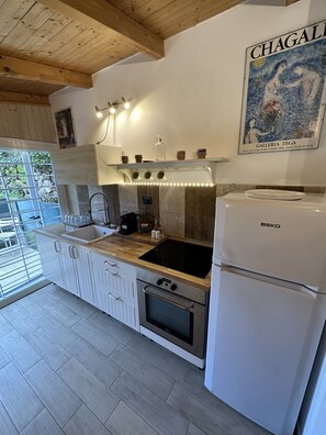 Une cuisine moderne avec des meubles blancs, une cuisinière noire et un réfrigérateur blanc.