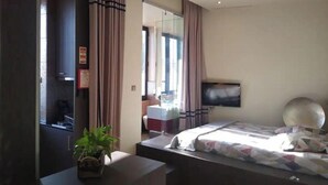 Een moderne hotelkamer met een bed, een televisie, een bureau en een potplant.