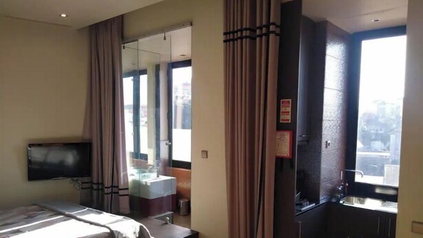 Een hotelkamer met een bed, televisie, badkamer en een kleine kitchenette.