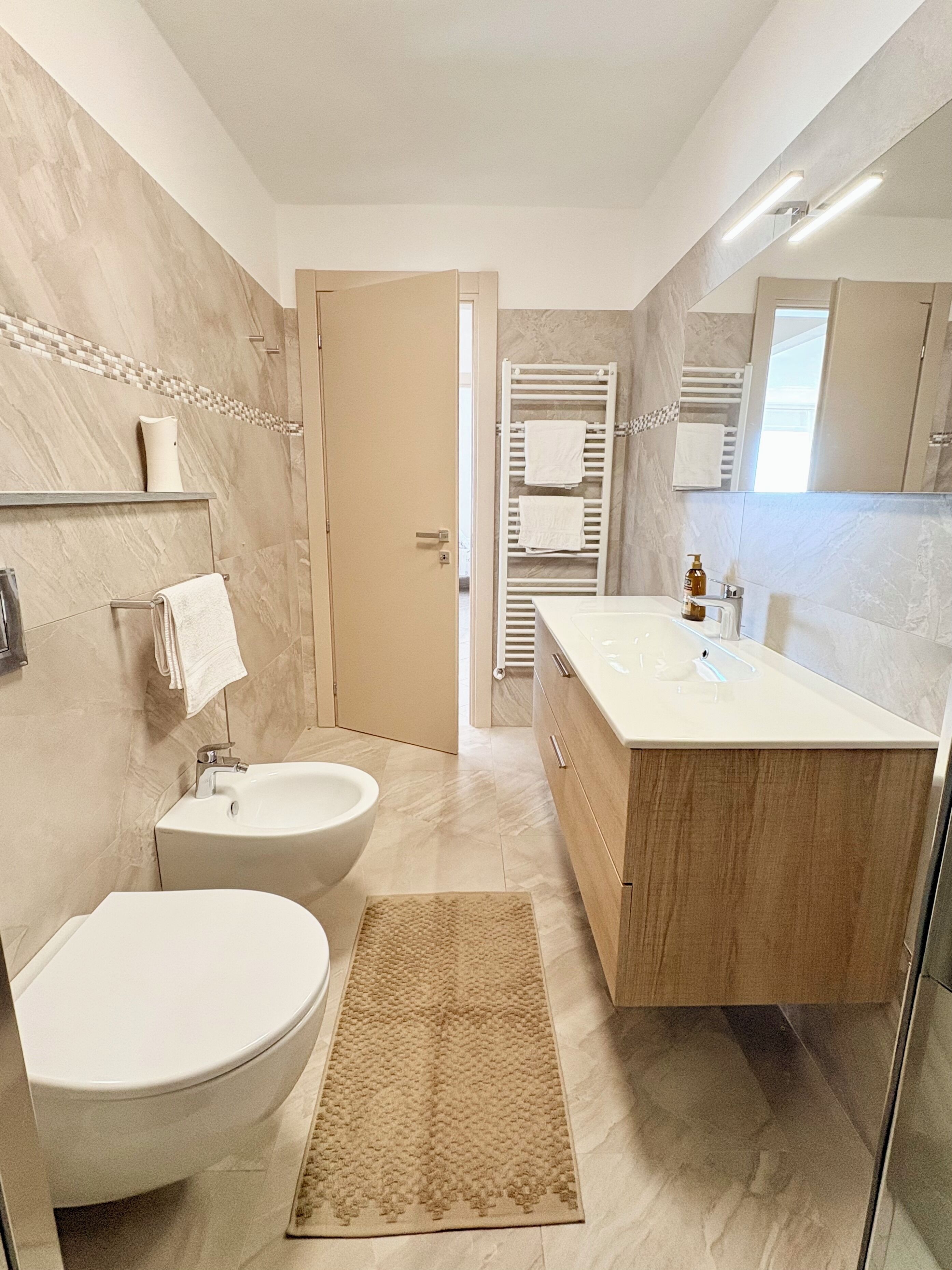 A modern bathroom with a toilet, bidet, vanity, and a shower area.
