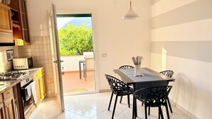 A modern kitchen with a dining area, including a table with chairs and a hanging light fixture.