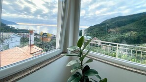A balcony with a view of a lake and hills, potted plants, and a railing.