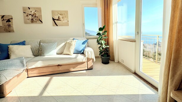 A modern living room with a sofa, a potted plant, and artwork on the wall.