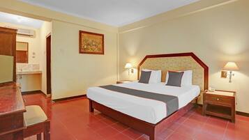 A hotel room with a large bed, bedside tables, a desk, and a chair.