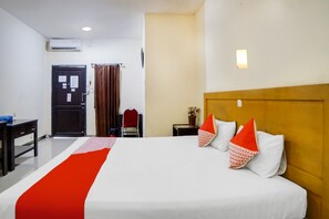 A hotel room with a large bed, a wooden headboard, a desk, and a chair. - OYO 91878 Cherry Red Hotel (Medan)