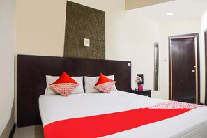 Una habitación de hotel con una cama grande, un cabecero oscuro y una colcha roja y blanca.