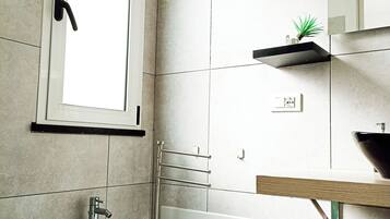 Une salle de bain moderne équipée de toilettes, d’un bidet et d’un lavabo doté d’un plan de travail en bois.