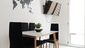 A dining area with a world map, a flat-screen TV, and a hanging light fixture. - Kolossoi Guest House (Cabras)