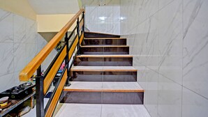 Una escalera con barandilla de madera, paredes de mármol y suelo de baldosas.