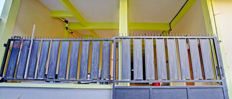 A balcony with a metal railing, a grey wall, and a yellow ceiling.