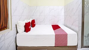 Una habitación de hotel con una cama, ropa de cama blanca y roja, y una pared con azulejos de mármol.