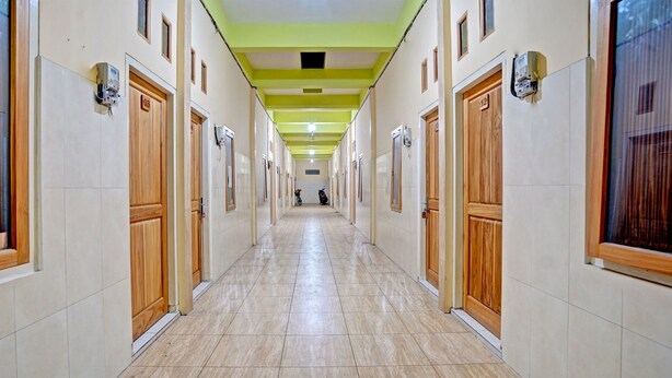 Un pasillo largo y estrecho con puertas de madera y pisos de baldosas, que conduce a una escalera.