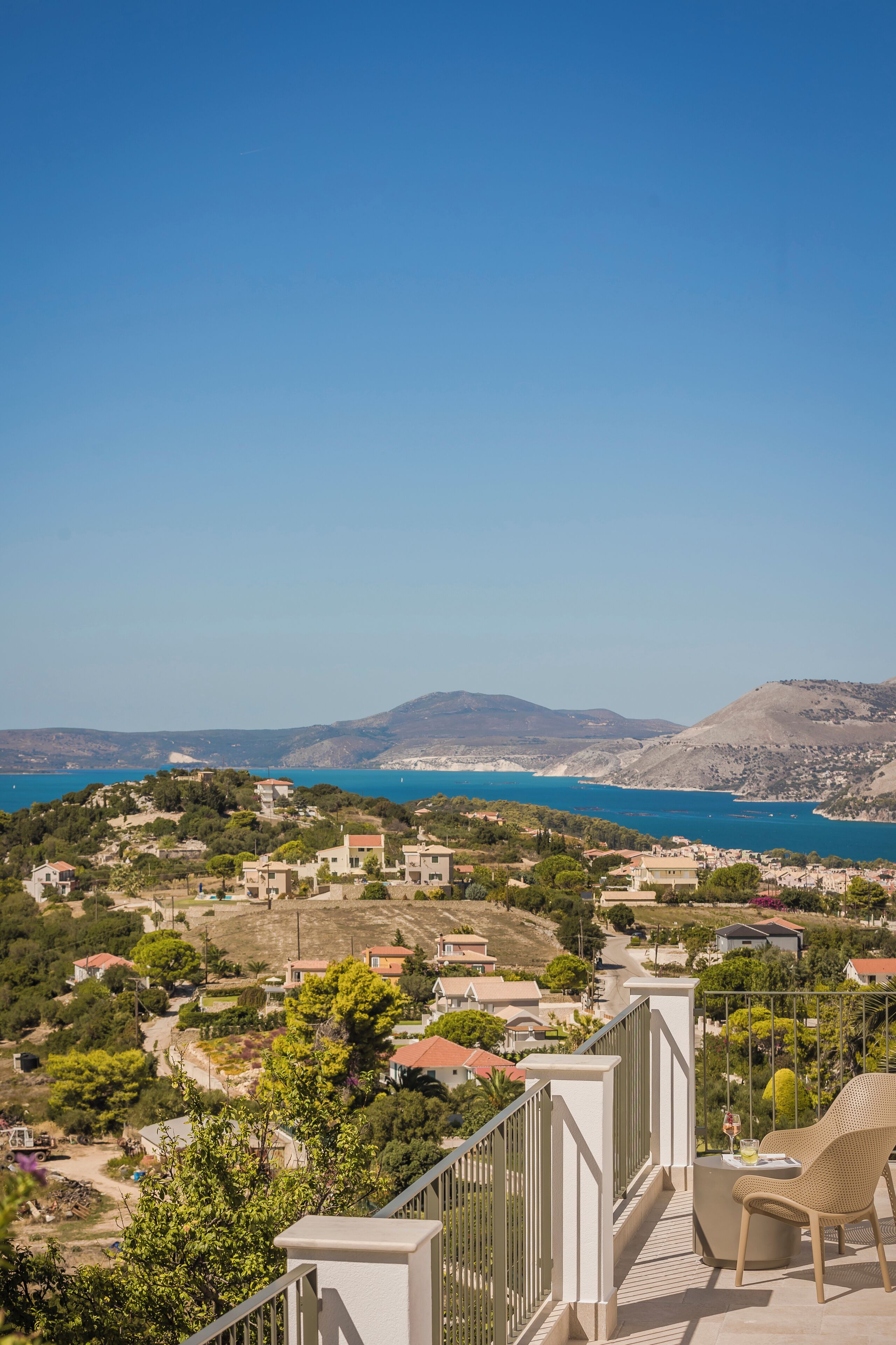 A balcony with a view of a coastal town and mountains.