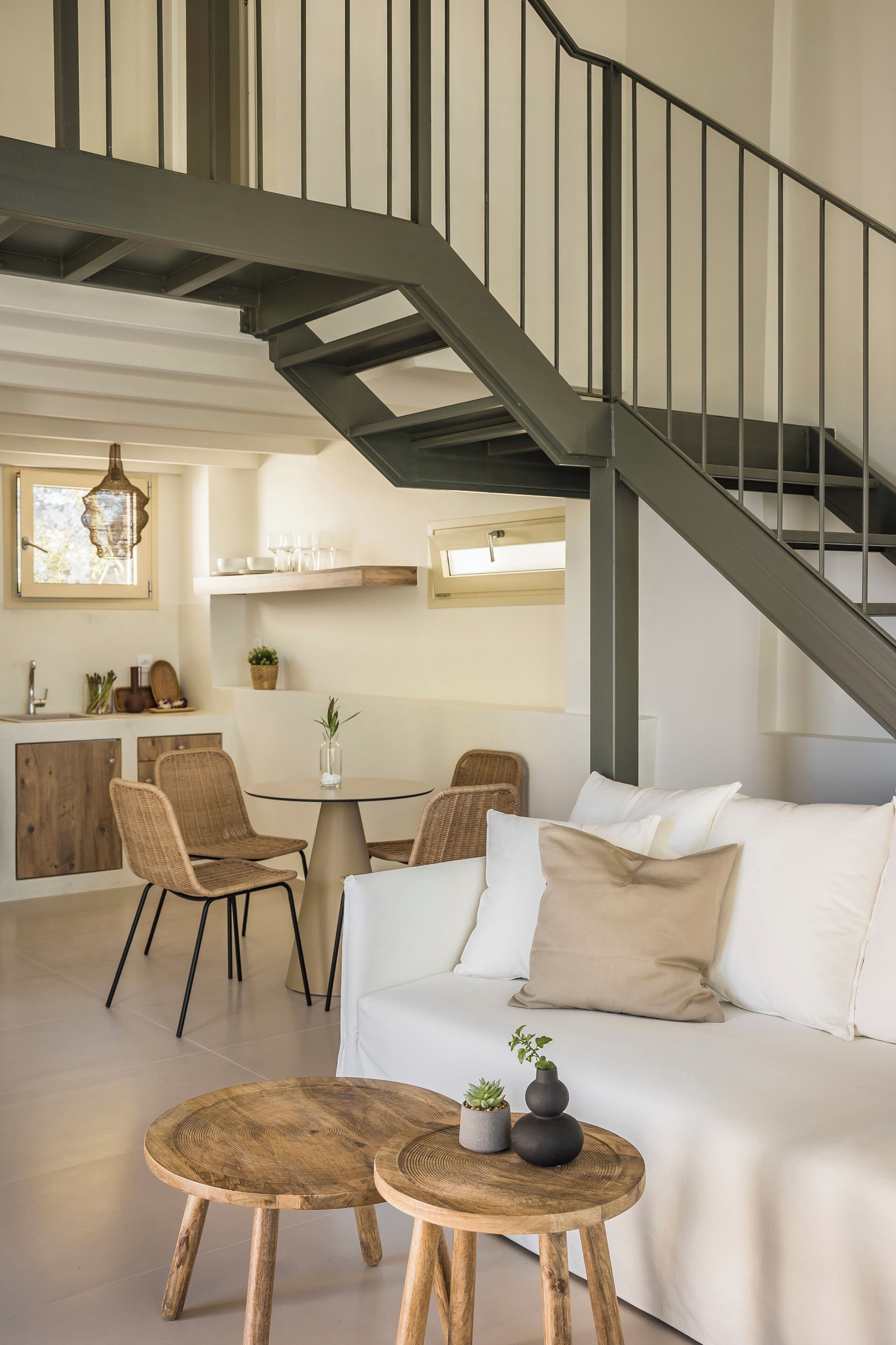 A modern living room with a staircase, a dining area, and a kitchen.