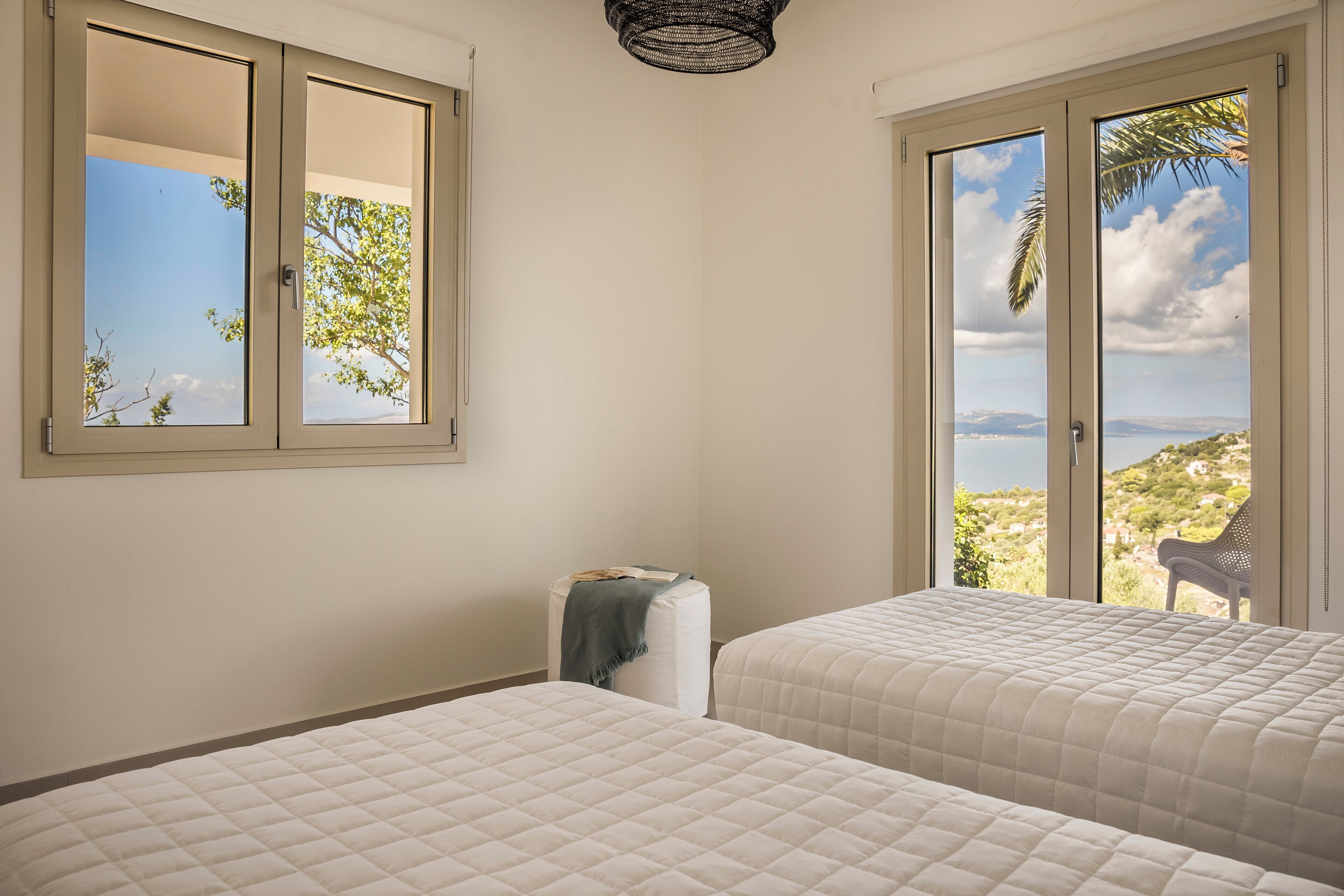 Ein Schlafzimmer mit zwei Betten, einem Fenster und Blick ins Freie.