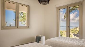 Ein Schlafzimmer mit zwei Betten, einem Fenster und Blick ins Freie.