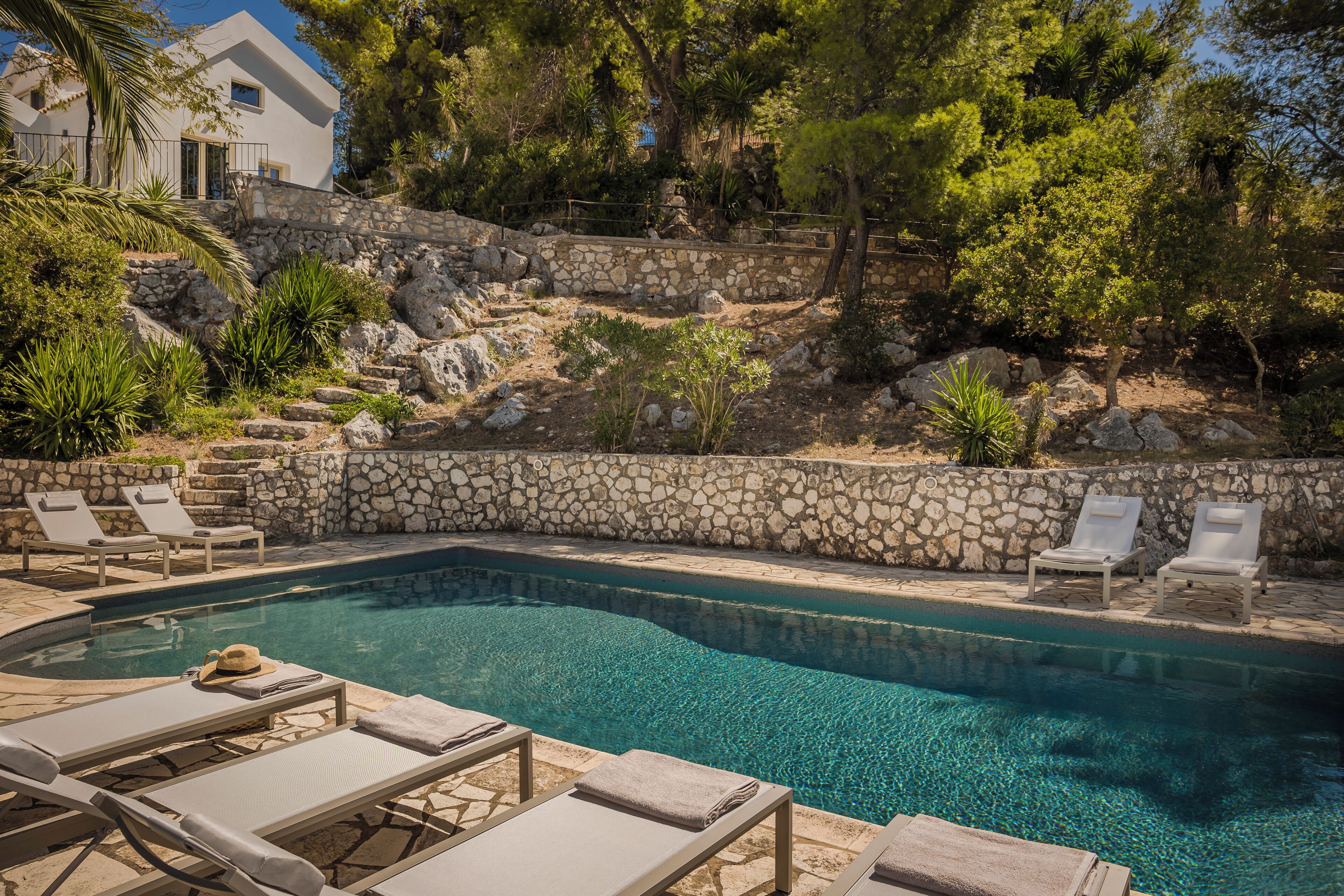A swimming pool with stone walls and lounge chairs.