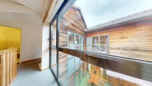 Un interno moderno con un balcone in vetro affacciato su pareti esterne in legno.