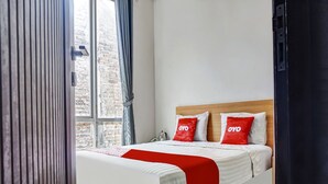 A neatly made bed with white and red bedding, a wooden headboard, and two pillows with "OYO" branding. - Capital O 91140 Ayodya Kebon Jeruk (Jakarta)