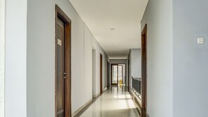 A long, narrow hallway with doors on both sides, a tiled floor, and a light-colored ceiling. - Capital O 91140 Ayodya Kebon Jeruk (Jakarta)