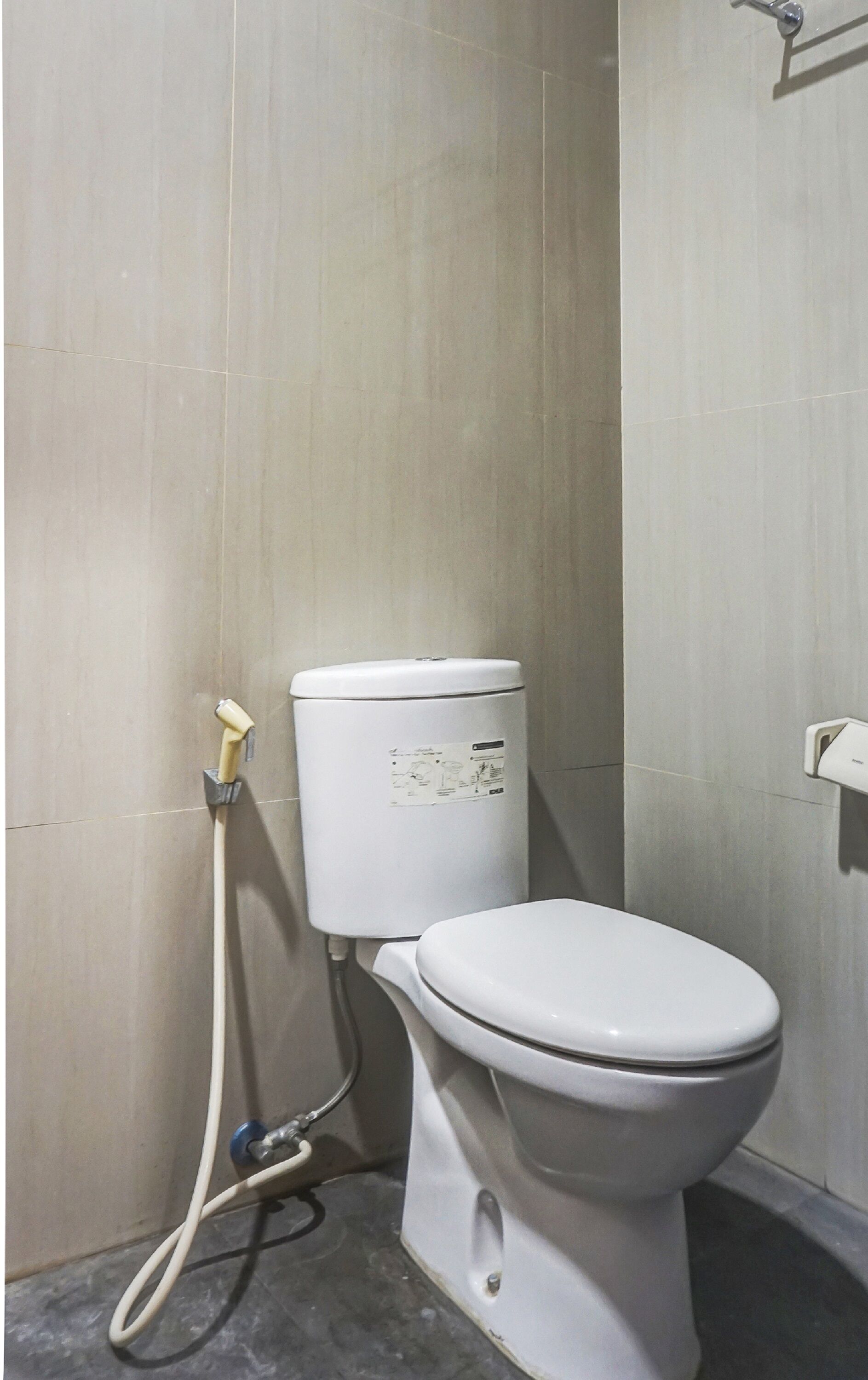 Un inodoro blanco con panel de control y asiento bidé en un baño con paredes de azulejos.