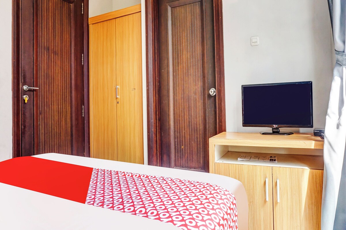 Una habitación de hotel con una cama, un escritorio con una computadora y dos armarios de madera.