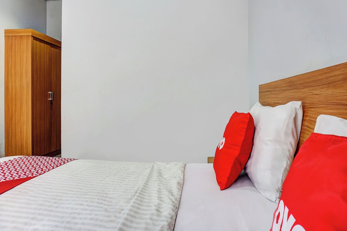 A hotel room with a bed, a wooden wardrobe, and a white wall.