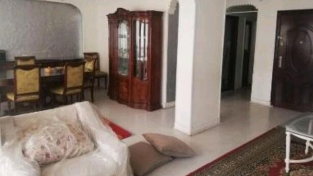 Ein geräumiges Wohnzimmer mit Essbereich, einem großen Holzkabinett und einem modernen Sofa.