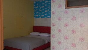 Une chambre avec une tête de lit rouge, un lit avec une literie grise, un mur jaune, un mur bleu orné de motifs de nuages et un mur à motifs floraux.