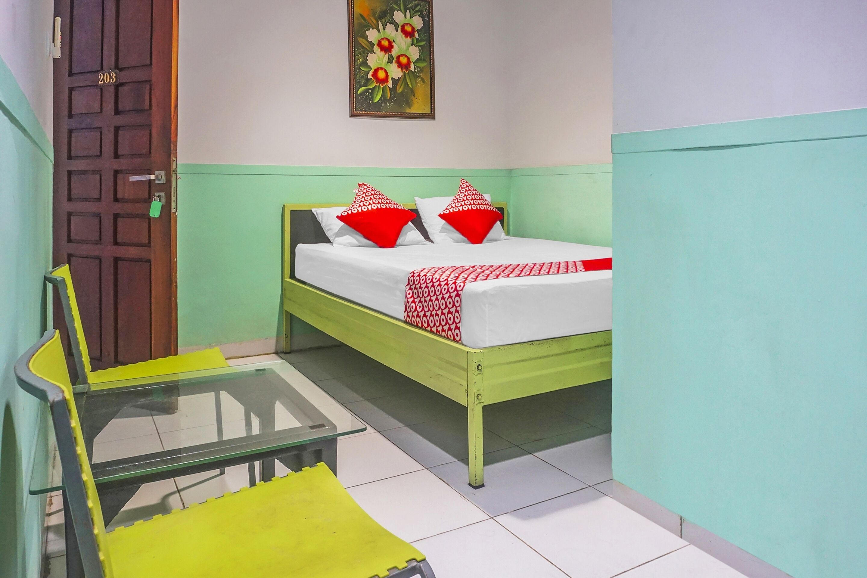 A small room with a bed, a glass table, and a chair.
