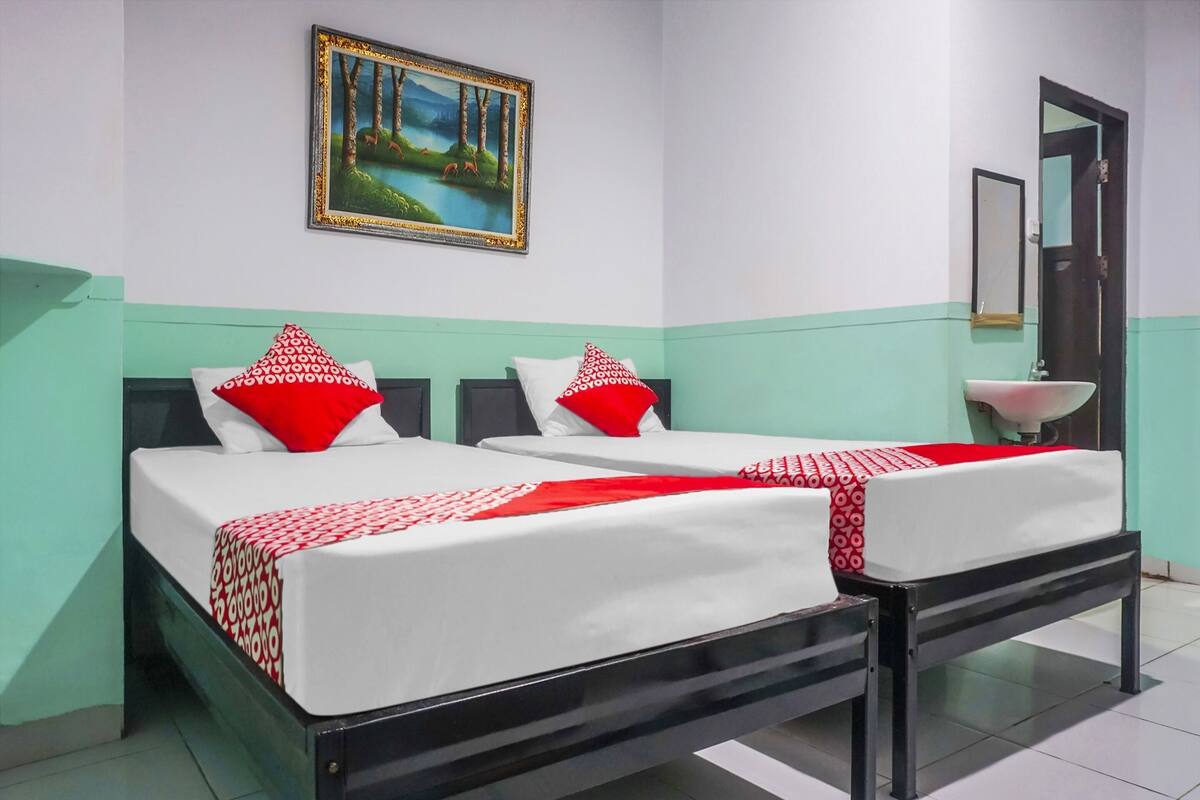 Une chambre d’hôtel avec deux lits, un tableau, un lavabo et un miroir.