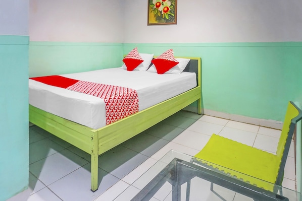 A bed with a green frame, white bedding, and red and white patterned pillows.