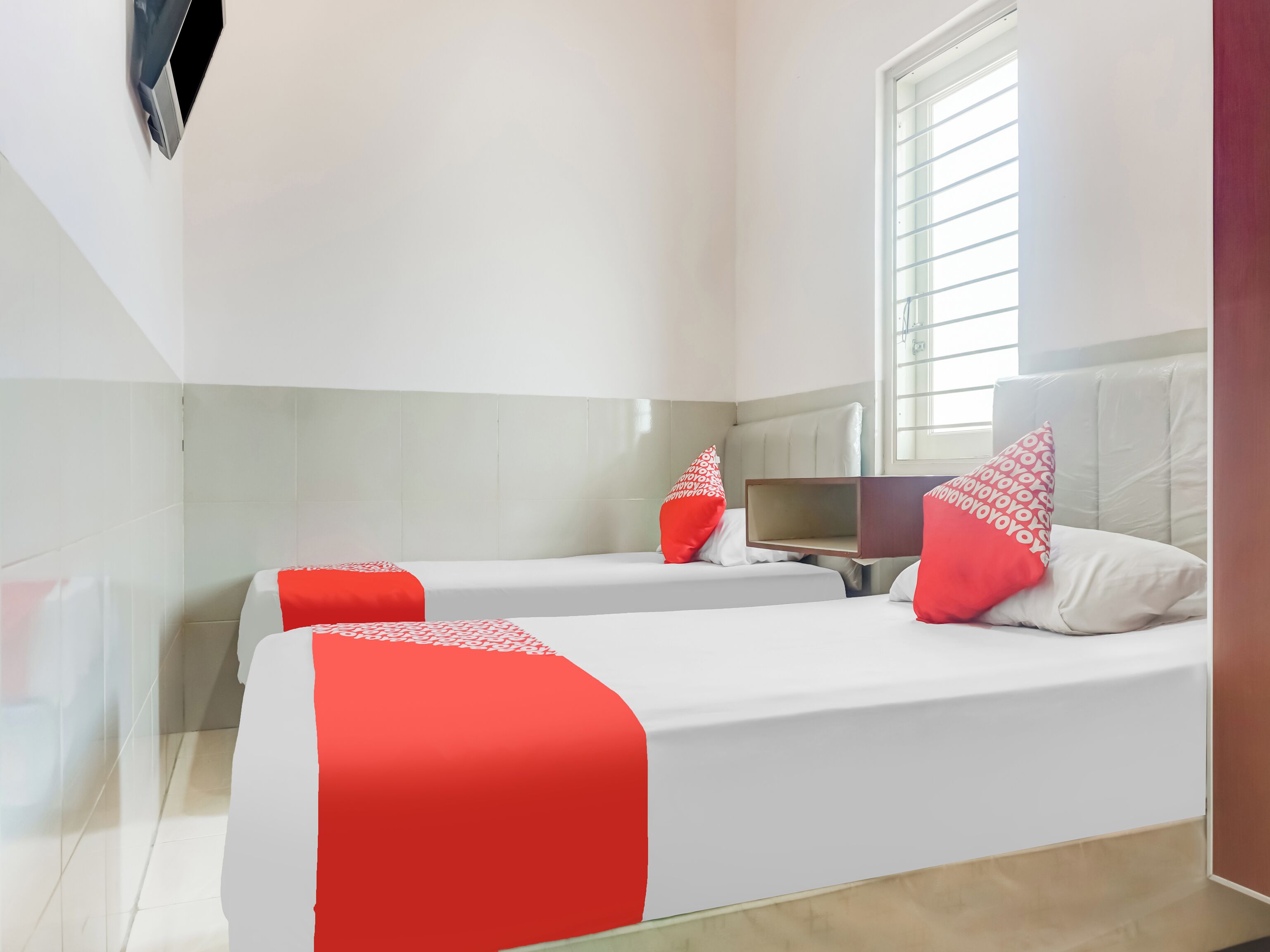 A hotel room with two beds, a large mirror, and a window with blinds.
